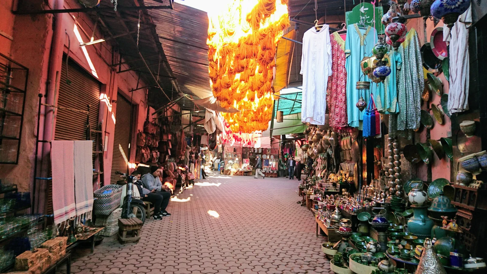 Marrakech street with local shops, people and warm terracotta architecture
